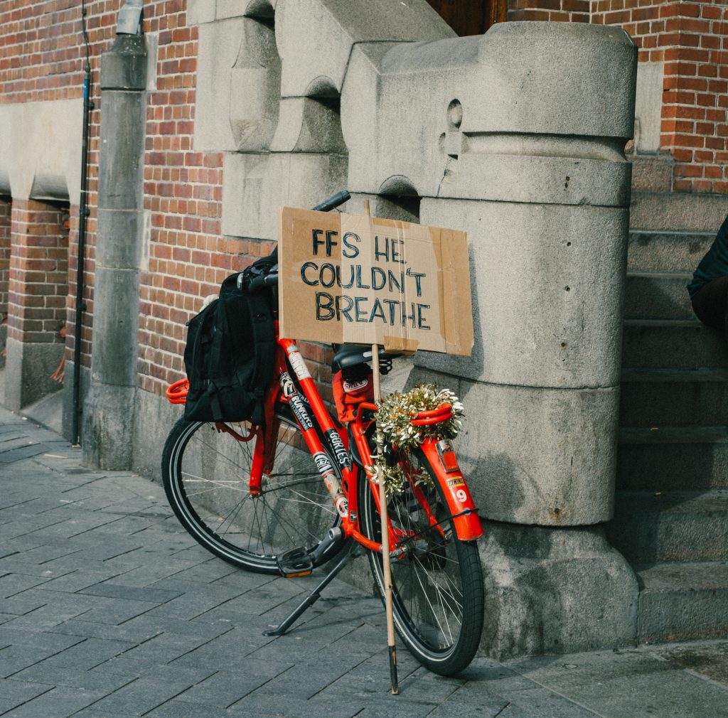 An orange bicycle decked with flowers and a sign reading "FFS He Couldn't Breathe"