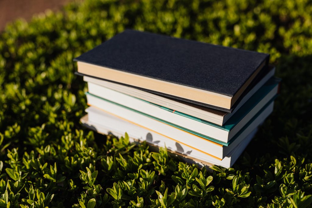 A stack of books on a mat of greenery.